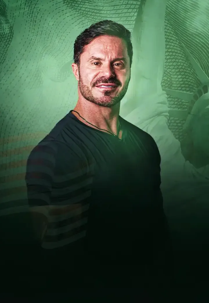 Renato Cariani diante de fundo verde com a Estátua da Liberdade ao fundo.